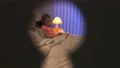 The boy and a girl laying on the bed. evening night time, view through a keyhole 4k or 4k+ Resolution
