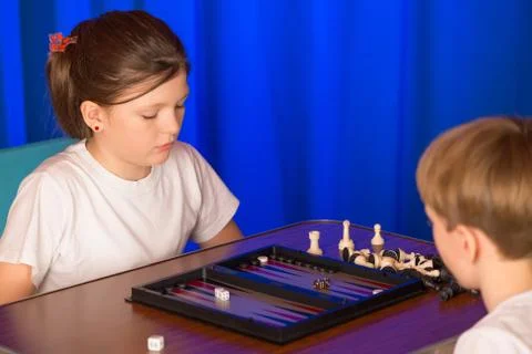 Boy and girl playing a board game called Backgammon Stock Photos