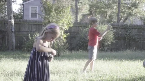Boy and girl playing with silly string in yard Stock Footage