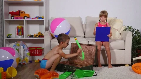 Boy and girl put things in a suitcase on the sea Stock Footage