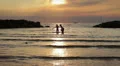 a boy and girl into the sea at sunset chases and jokes with water HD Footage