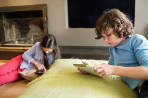Boy and a girl using electronic gadgets at home Stock Photos