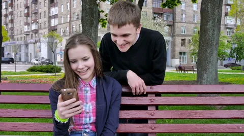 Boy And Girl Using Mobile Phone. Laughing.Outside. Stock Footage 62773808