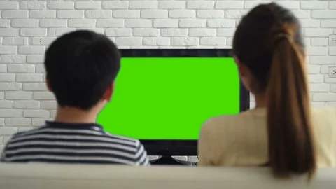 Boy and girl watching television with green screen in living room Stock Footage