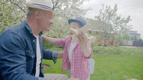 Boy and granddad are playing wooden airplane on the lawn Video stock 78556553