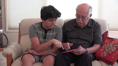 Boy and grandfather using a tablet in living room Stock Footage 89375452