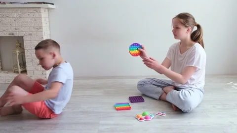 Boy and gril playing with anti stress sensory toy popit at home. Silicone Stock Footage 156844997
