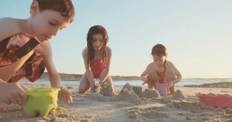 Boy and his two sisters playing with sand casltes on the beach Stock Footage 65259372