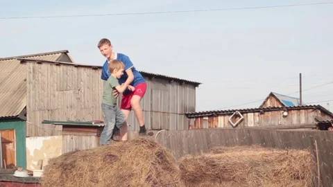 The boy and his younger brother jump in the hay Stock Footage 74947553