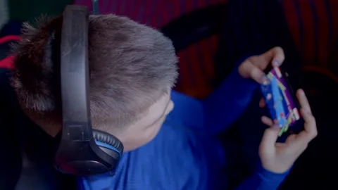 A boy and a man, both gaming with headphones, show gamings appeal Stock Footage 311075813