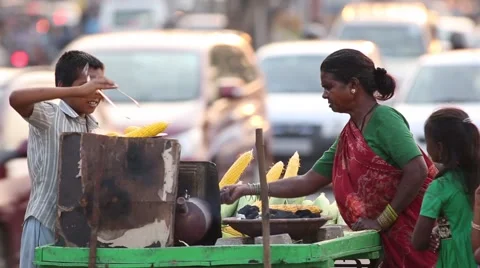 Boy and mother sells corn on a push cart on the streets Stock Footage 63621332