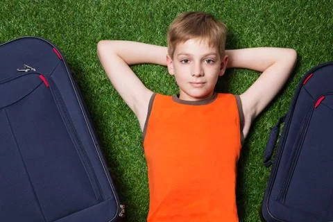 Boy and siutcases th lying on green grass close up Stock Photos