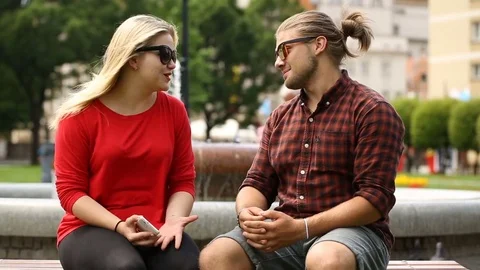 Boy answers cellphone while speaking with his girlfriend Stock Footage 77484289