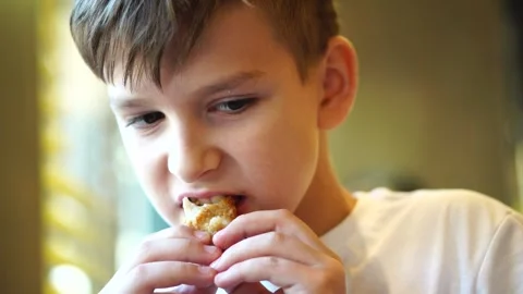 A boy with an appetite eats chicken nuggets in a cafe. face close-up Stock Footage 248377747
