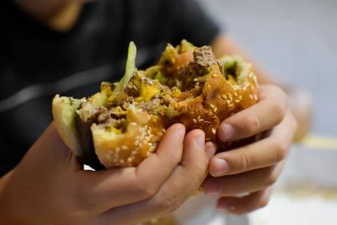 Boy with appetite eats delicious hamburger. child bites off large piece of sa Stock Photos