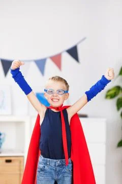 Boy with arms raised in super hero costume at home Stock Photos