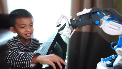 Boy asia constructs and programmes on computer and building a robot arm at home  Stock Footage 246182664