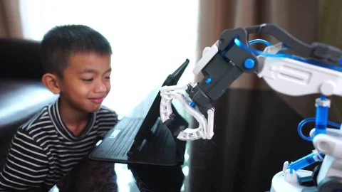 Boy asia constructs and programmes on computer and building a robot arm at home  Stock Footage 246182947