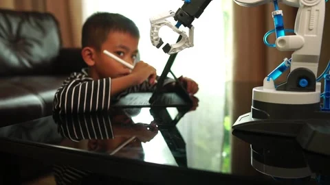 Boy asia constructs and programmes on computer and building a robot arm at home  Stock Footage 246184895