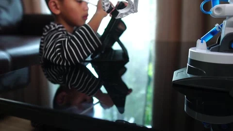 Boy asia constructs and programmes on computer and building a robot arm at home  Stock Footage 246185149