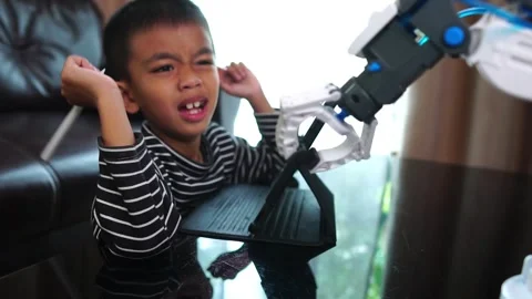 Boy asia constructs and programmes on computer and building a robot arm at home  Stock Footage 246185474
