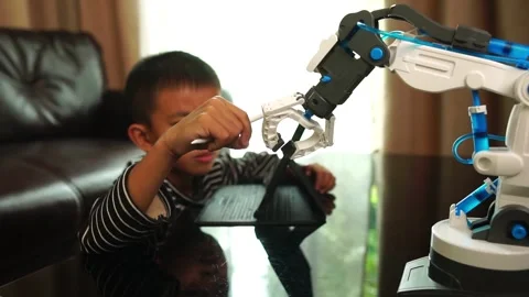 Boy asia constructs and programmes on computer and building a robot arm at home  Stock Footage 246187462