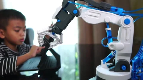 Boy asia constructs and programmes on computer and building a robot arm at home  Stock Footage 246187470