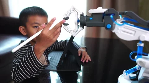 Boy asia control robot arm on Digital tablet Stock Footage 246182656