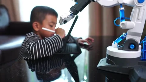 Boy asia control robot arm on Digital tablet Stock Footage 246182945