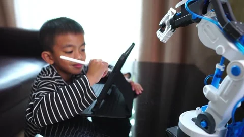 Boy asia control robot arm on Digital tablet Stock Footage 246183669