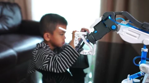 Boy asia control robot arm on Digital tablet Stock Footage 246186332