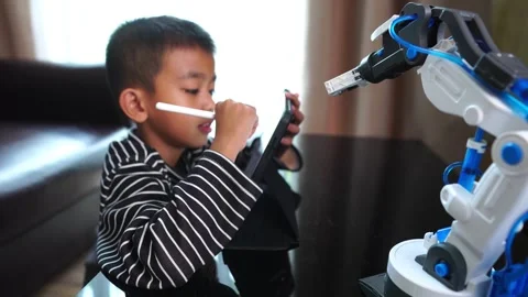 The boy asia programming a robot on his laptop Stock Footage 246183773