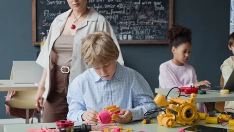 Boy Assembling Robot with Teacher Helping in Robotics Class Stock Footage 339200523