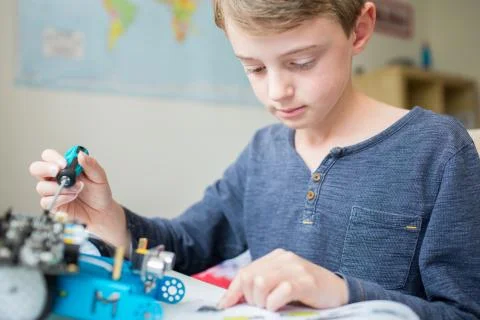 Boy Assembling Robotic Kit In Bedroom Stock Photos