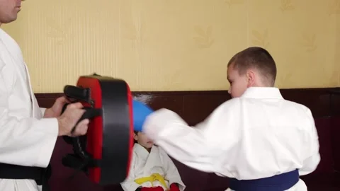 A boy athlete actively hits the simulator in the hands of a trainer Stock Footage 268829968