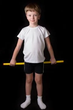 Boy athlete performs exercises with gymnastic stick in the gym Stock Photos
