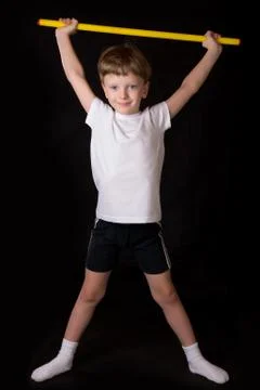 Boy athlete performs exercises with gymnastic stick in the gym Stock Photos