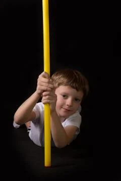 Boy athlete performs exercises with gymnastic stick in the gym Stock Photos