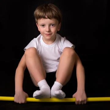 Boy athlete performs exercises with gymnastic stick in the gym Stock Photos