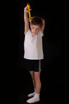 Boy athlete performs exercises with gymnastic stick in the gym Stock Photos