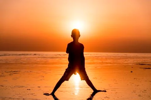 Boy in backlight in sunset with sun in background Stock Photos