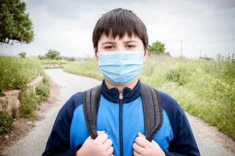 Boy with backpack and blue jacket prepared to go to school with the mask on h Stock Photos