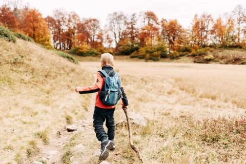 A boy with a backpack and a stick has fun on a hiking trail on a weekend. Foto stock