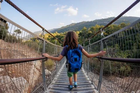 Boy with a backpack crosses the canyon through a rope bridge. traveling with  Stock Photos