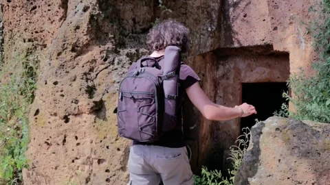 Boy with backpack entering and exploring an ancient catacomb Stock Footage 253347417
