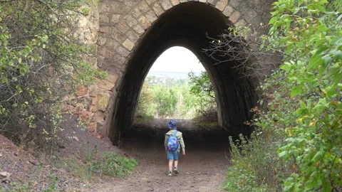 Boy with backpack entering stone tunnel Stock-Footage 317327333