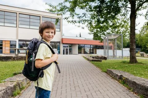 A boy with a backpack on his back walks from school. Children go to school and Stock Photos