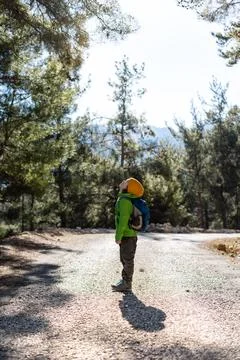 A boy with a backpack in the middle of a forest road, a child is exploring wi Foto stock