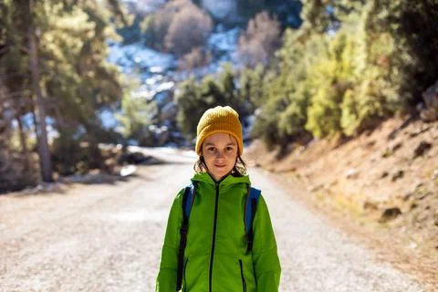 A boy with a backpack in the middle of a forest road, a child is exploring wi Stock Photos