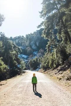 A boy with a backpack in the middle of a forest road, a child is exploring wi Stock Photos